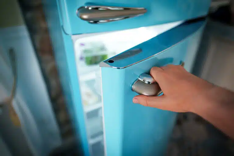 Homme ouvre la porte du r&eacute;frig&eacute;rateur r&eacute;tro cong&eacute;lateur
