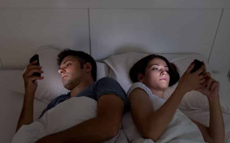 couple au lit sur son t&eacute;l&eacute;phone routine ennui