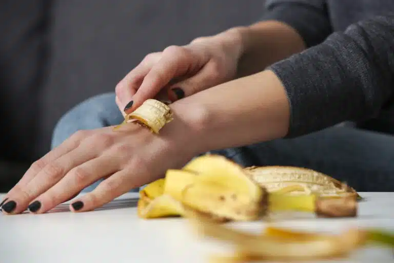 Femme frottant la peau de banane sur ses mains pour hydrater sa peau. Z&eacute;ro d&eacute;chet utilisations peaux de bananes