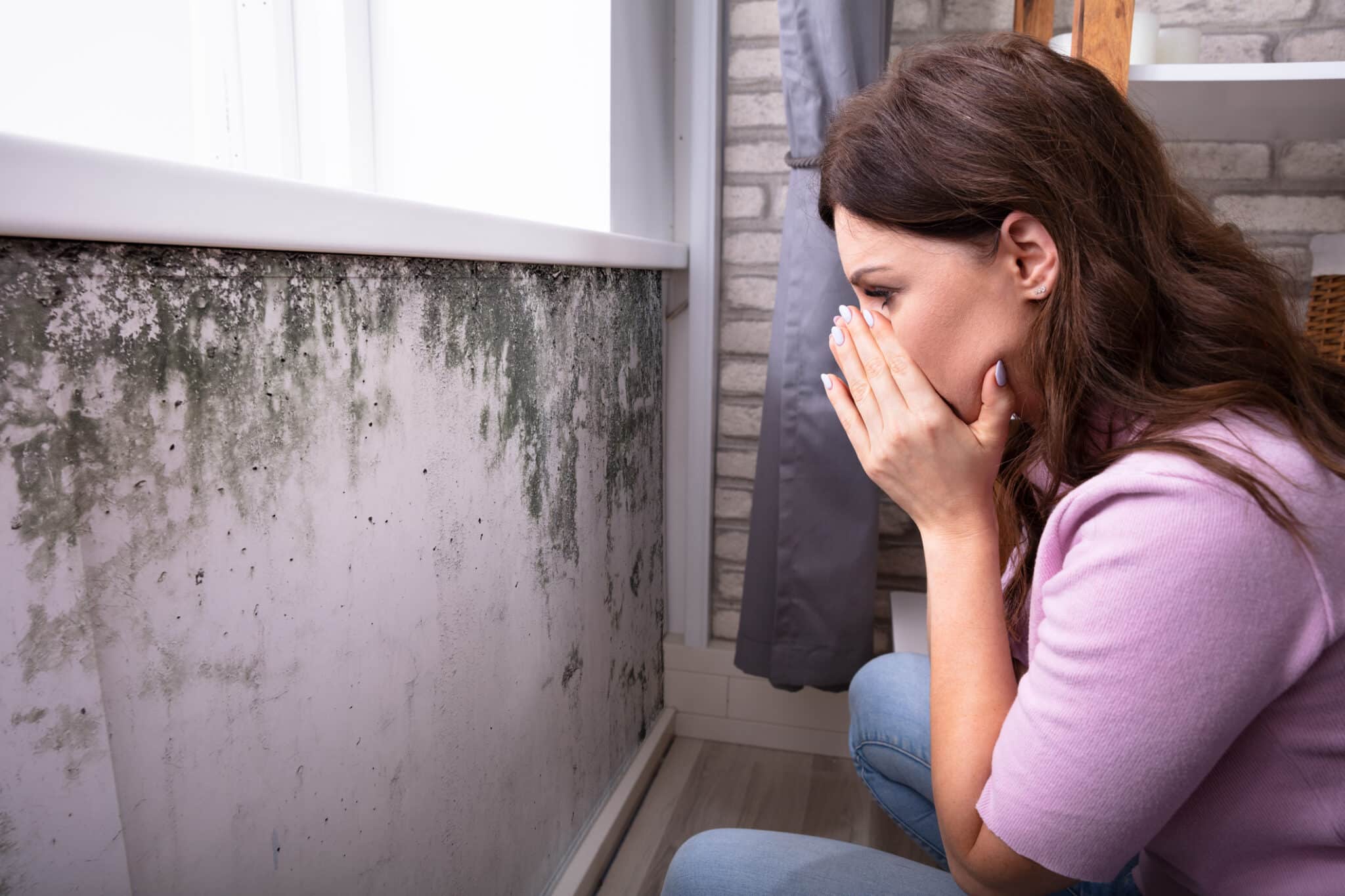 Femme choqu&eacute;e devant la moisissure sur le mur